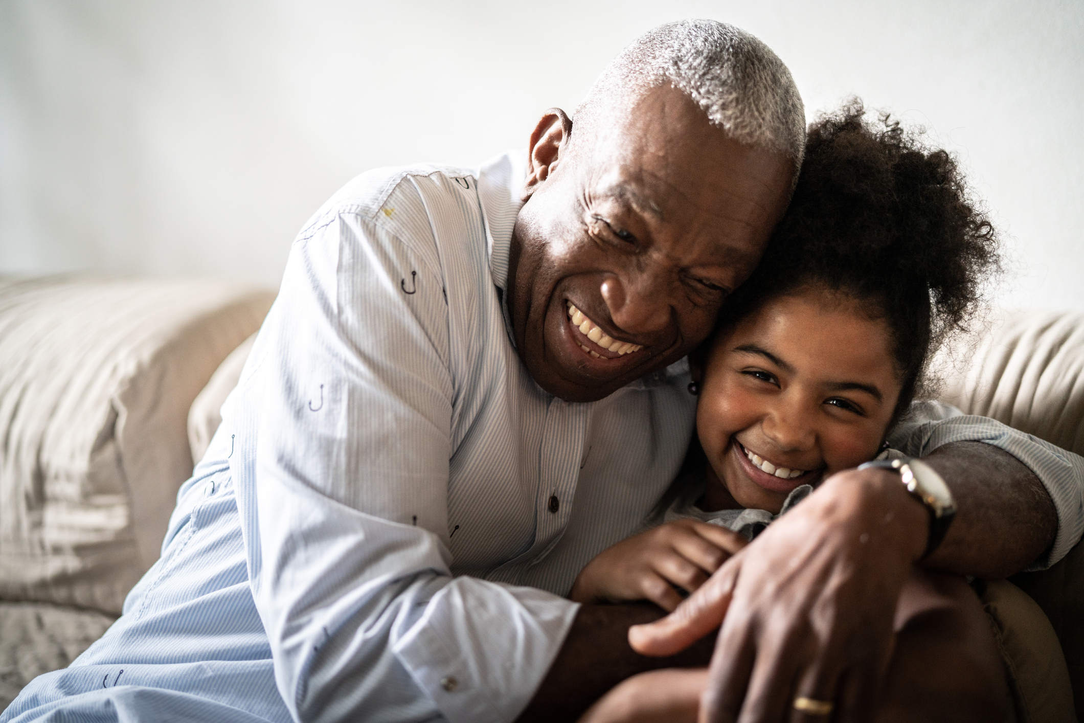 Portrait of grandfather embracing granddaughter at home